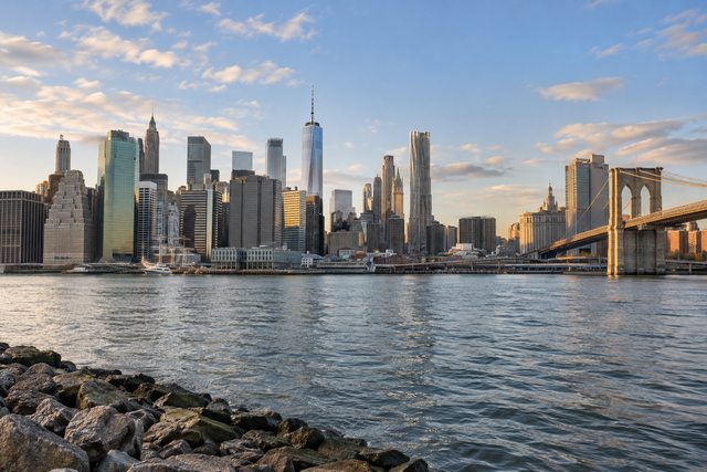 Lower Manhattan skyline and Brooklyn Bridge across the East River in afternoon light.